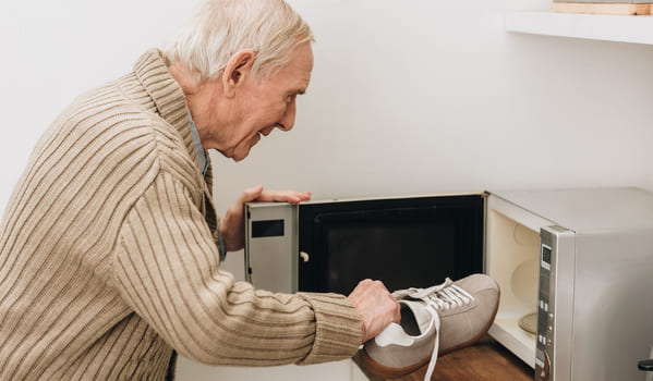 Ein Demenzkranker möchte seine Schuhe in die Mikrowelle legen.